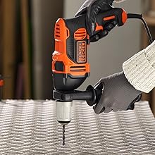 Un hombre perfora una lámina de metal con un taladro BLACK+DECKER.