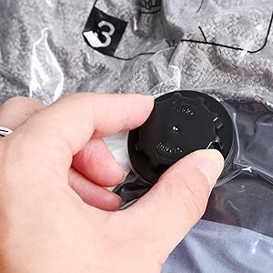 Mano que sostiene un pequeño dispositivo circular negro sobre un fondo metálico o plateado