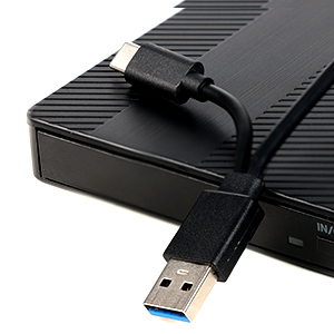 Primer plano de un dispositivo electrónico negro con un conector USB conectado, que muestra la textura de la superficie estriada y el puerto de conexión