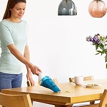 Una mujer aspira el polvo de una mesa