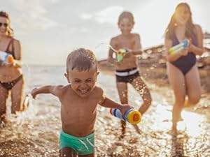 Grupo disfrutando del tiempo libre en una playa durante la hora dorada, con olas y una costa rocosa de fondo.