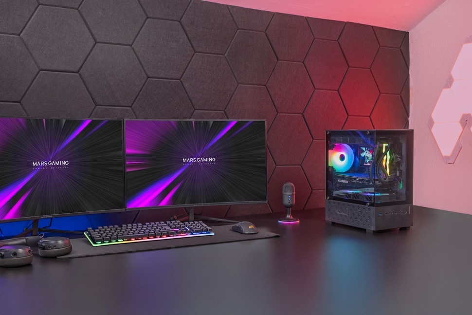 Configuración para juegos con paneles de pared hexagonales iluminados con iluminación RGB en tonos morados y azules. Muestra un escritorio con teclado y monitor contra una pared decorativa.