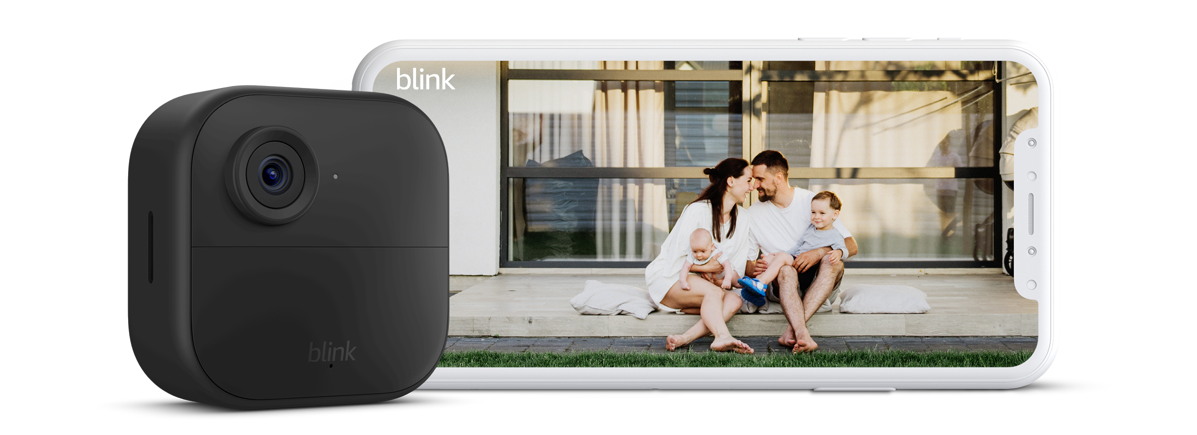 Cámara Blink Outdoor 4 y móvil en horizontal sobre fondo blanco. En la pantalla del móvil, se ve una foto de una pareja con niños pequeños en su jardín.