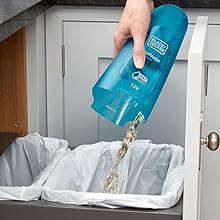 una persona echa la basura de una aspiradora de mano en una papelera