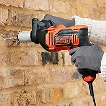 Una persona perfora una pared de ladrillo con un taladro BLACK+DECKER.
